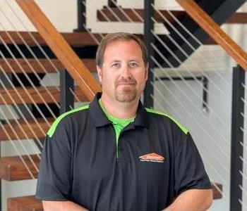 Male employee with dark hair smiling in front of SERVPRO sign