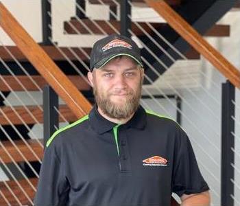Male employee with blonde hair in front of a SERVPRO sign