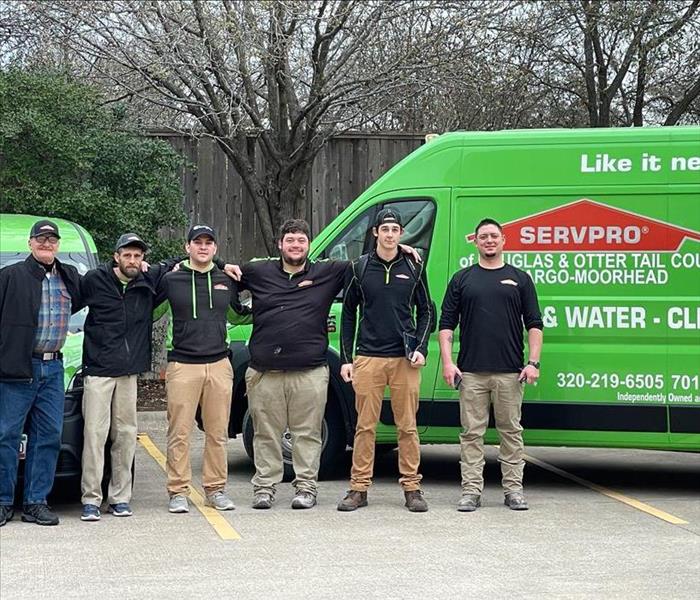 six men standing in front of a SERVPRO truck outside,